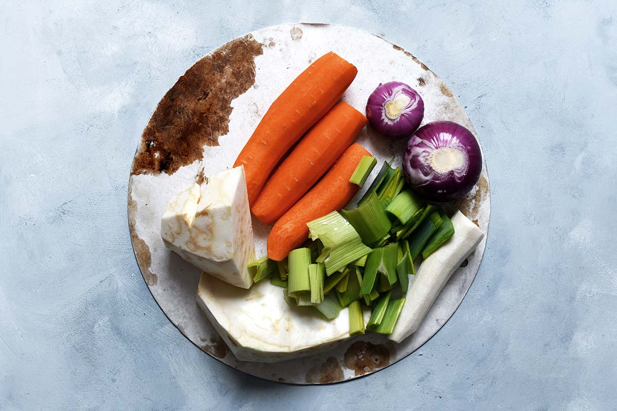 Suppengrün für Hühnerbrühe: Möhren, Lauch, Sellerie und Zwiebeln vorbereiten